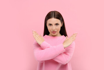 Stop gesture. Woman with crossed hands on pink background