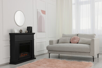 Black stylish fireplace near comfortable sofa in cosy living room