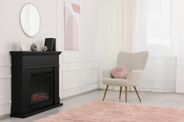 Black stylish fireplace near soft armchair in cosy living room