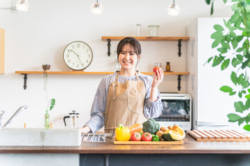 キッチンに立つエプロン姿の日本人女性（トマト）

