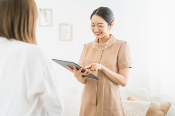 エステサロン・ネイルサロンの受付で説明をする女性（タブレットPC）
