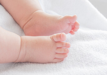 Tiny newborn baby feet closeup on a white blanket