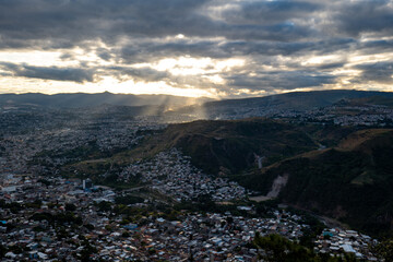 Panoramic View of Tegucigalpa City with Hills, Houses, Buildings, and Trees Surrounded by Green Mountains on a Cloudy Day