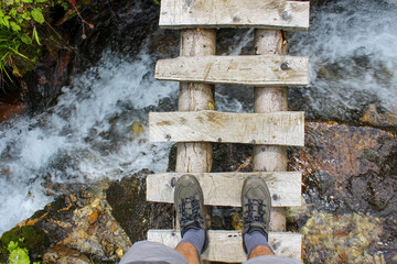 POV. Wooden bridge in mountains. Hiking. Exploration. Feeling free.