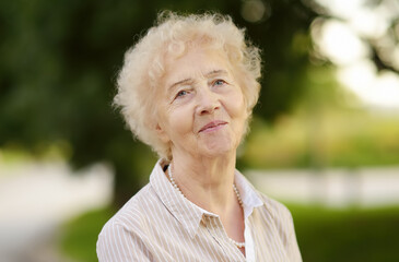 Outdoor portrait of beautiful senior woman with curly white hair