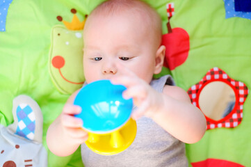 Fototapeta na wymiar Little baby play with bright rattle toy. Educational toys for childs