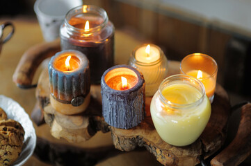 Scented candles burn beautifully on a wooden table. Cute cozy decoration of the living room.