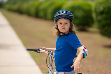 Fototapeta na wymiar Child riding bicycle. Little kid boy in helmet on bicycle along bikeway. Happy cute little boy riding bicycle in summer park. Child in protective helmet for bike cycling on bicycle. Kid riding bike.