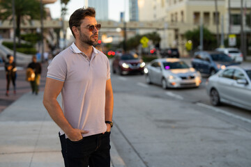 Man model in fashion in stylish polo walking on the city. Guy walks on the street. Urban fashion...