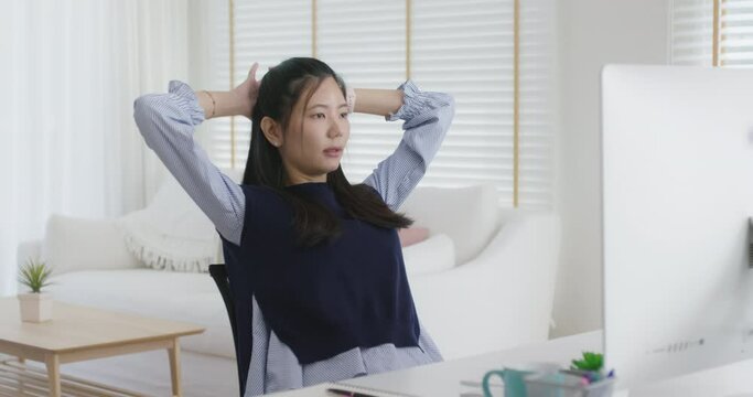 Asia people workforce young woman remote work at home office sit easy relax enjoy break time life balance put hands behind head and lean back on cozy desk. Teen girl stress relief look at desktop PC.