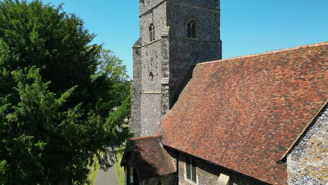 A rising boom-shot of St Mary's church, which ascends above the tower to unveil the union flag flying on the tower, and the village of Chartham.