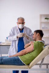 Obraz premium Young male patient visiting old male doctor in vaccination conce