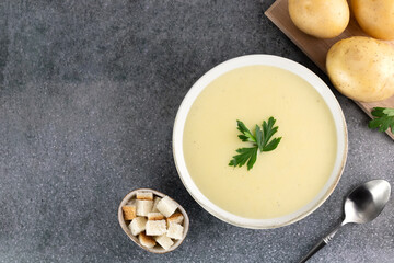 Bowl of creamy potato soup with ingredients on a gray background. Top view. Copy space. French vichyssoise soup.