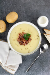 Potato soup puree with bacon, croutons and ingredients on a gray background. Top view. French vichyssoise soup.