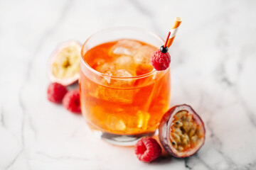 Fresh sparkling berry drink with passion fruits and raspberries in wine glass.