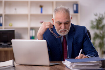Fototapeta premium Old male employee working in the office