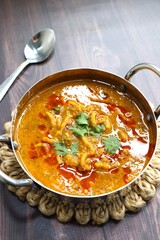 Traditional Sev bhaji or sev tamatar nu Shaak. its a sweet & spicy tomato curry topped with sev. Sev is a crisp fried gram flour vermicelli. Served with chopped onion and lemon. with Copy space.