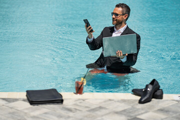 Businessman in suit with laptop in swimming pool. Crazy business man swimming on summer vacation....