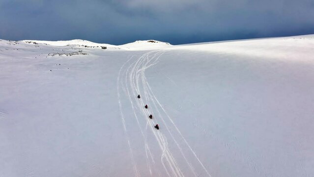 Aerial panoramic view of people riding snowmobiles on the icy ground of Myrdalsjokull glacier in Iceland