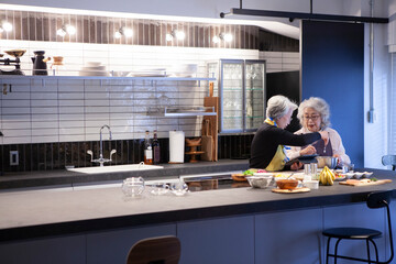 キッチンで二人で並んで調理をする仲の良いシニア女性