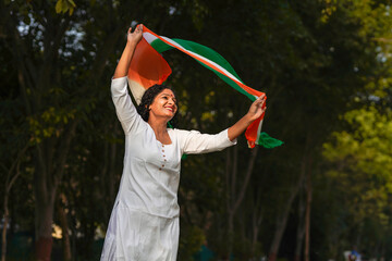 Indian woman waving tricolor cloth or odhani at park.