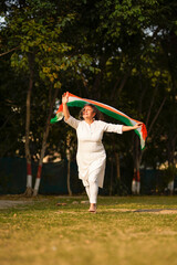 Indian senior woman waving tricolor cloth or odhani. celebrate national festival.