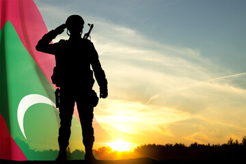 Silhouette of a saluting soldier with Maldives flag against the sunset. Background for National Holidays
