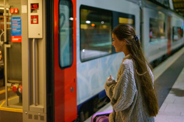 Little charming girl tourist is waiting for train at station in evening