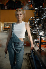 Fototapeta na wymiar Portrait of young woman mechanic with wrench in hand at motorcycle workshop