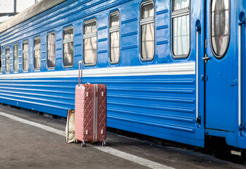 A lone suitcase stands in front of a railway carriage....
