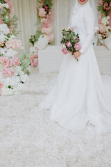 The bride holds a wedding bouquet of flowers in her hands.