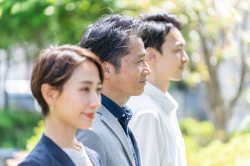Fototapeta premium 屋外の新緑の前に立つビジネスマンたち