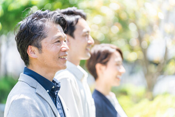 屋外の新緑の前に立つビジネスマンたち