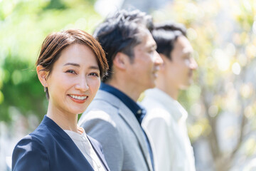 屋外の新緑の前に立つビジネスマンたち