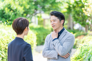 屋外の新緑の前に立つビジネスマンたち