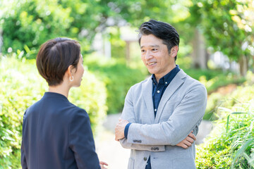 屋外の新緑の前に立つビジネスマンたち