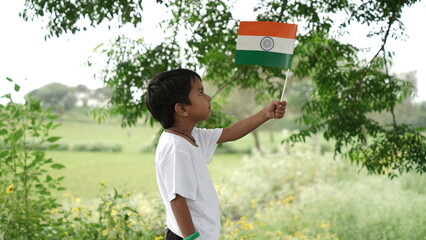 Cute little boy with Indian National Tricolour Flag, Isolated over nature background. Suitable for...