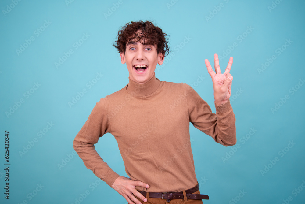 Wall mural emotional guy is surprised, happy and sad posing in the studio on a blue background.