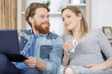 couple with pregnant woman using laptop computer together
