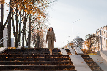 Obraz premium Young woman walking down the steps on street through the autumn city