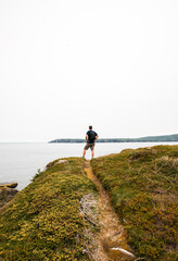 Obraz premium Man standing on hill overlooking the ocean in Newfoundland.