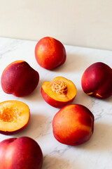 Ripe nectarines in the sun on a white tile with a tan background