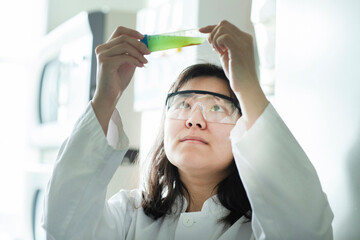 young  scientist female controlling a green liquor in tube