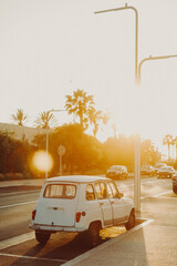 A vintage white car is backlit by the setting sun in Morocco.