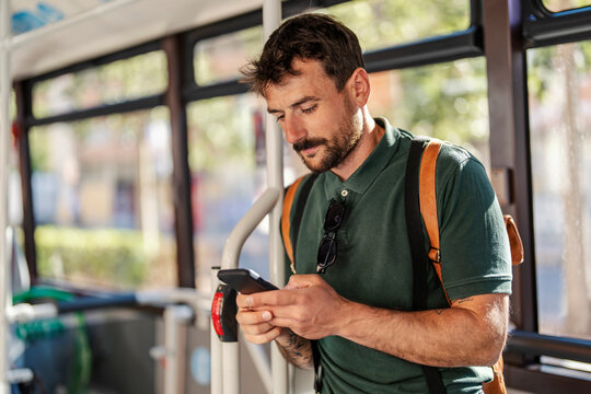 A man in public bus is using his phone.