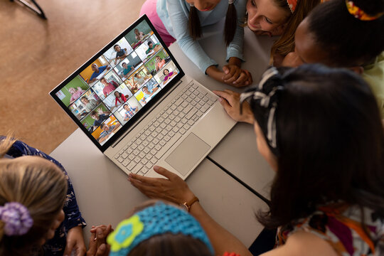 High angle view of diverse teacher and students studying over video conference on laptop in school