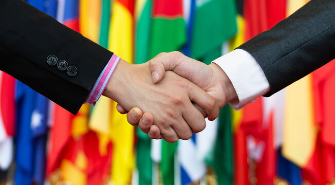 Businessmen shaking hands in front of the multi - national flags