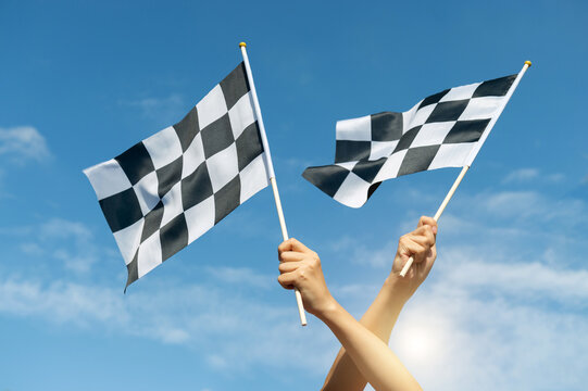 Two checkered race flags in hand