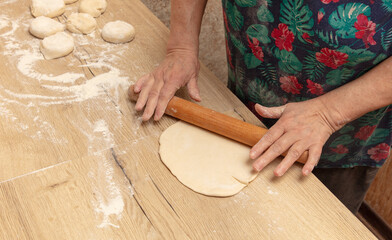 Close-up of an elderly woman rolling dough with a rolling pin