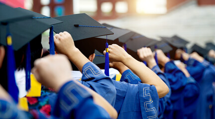 Back of graduates put hands up in a row during commencement